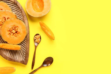 Ahşap tahta, tatlı kavunlar ve sarı arka planda bir kaşık tohum.