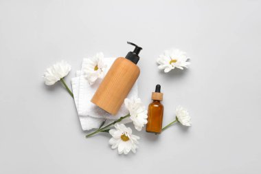 Hafif arkaplanda kozmetik ürünleri, havlu ve papatya çiçekleri kompozisyonu