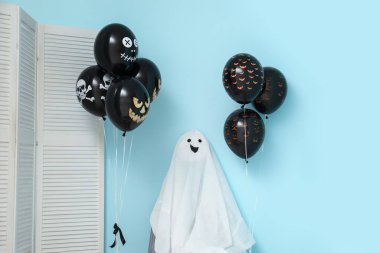 Farklı siyah Cadılar Bayramı balonları, katlanan ekran ve mavi duvarın yanındaki hayalet.