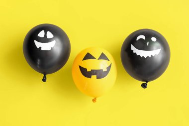 Sarı arka planda farklı komik Cadılar Bayramı balonları