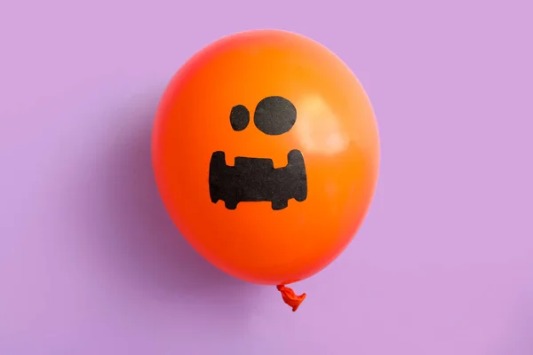 Funny Halloween balloon on lilac background