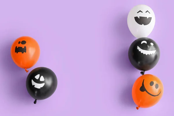 Different funny Halloween balloons on lilac background