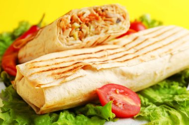 Sarı arka planda marul ve domatesli lezzetli shawarma.