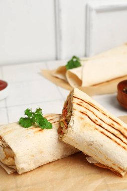 Beyaz fayansların üzerinde maydanozlu, lezzetli shawarma soslu kağıt.