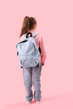 Pembe arka planda sırt çantası olan küçük okul kızı.