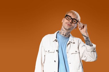 Renkli gözlüklü, dövmeli genç bir adam.