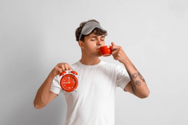 Çalar saati olan genç adam arka planda kahve içiyor.