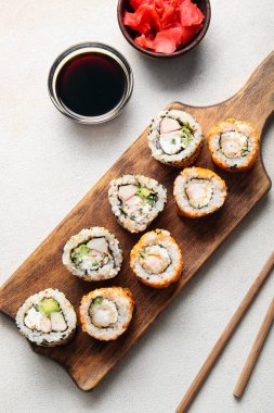 Nefis suşi ruloları, soya sosu ve açık arkaplanda zencefil.