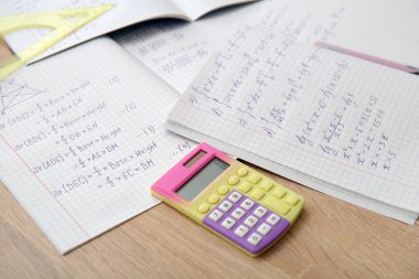 Matematik formülleri ve ahşap masadaki kırtasiye malzemeleriyle metin kitaplarını aç
