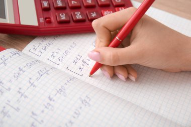 Matematik formüllerini ahşap masaya yazan kadın, yakın plan.