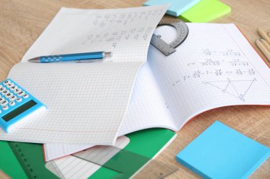 Matematik formülleri ve ahşap masa üzerindeki kırtasiye malzemeleriyle metin kitabını aç, kapat