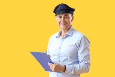 Sarı arka planda panosu olan olgun bir postacı.