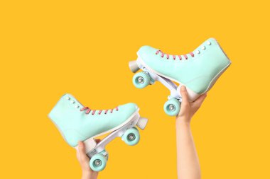 Turuncu arka planda patenli kadın eller.