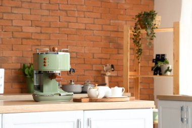 Modern kahve makinesi ve fincanlar mutfaktaki masada.