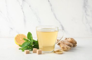 Beyaz arka planda limon ve nane aromalı bir bardak zencefil çayı.