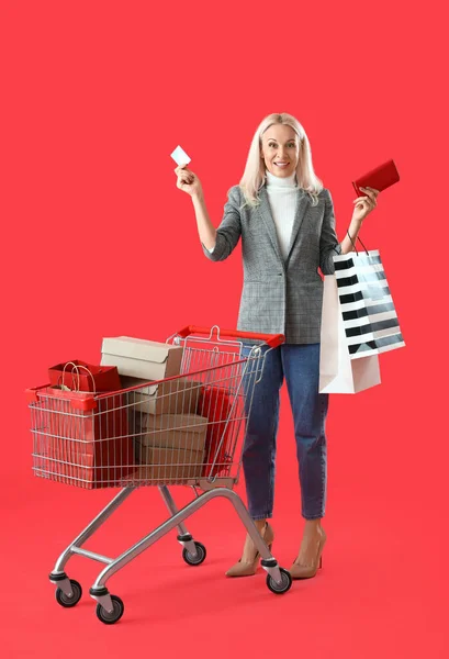 Rijpere Vrouw Met Credit Card Tassen Winkelwagen Rode Achtergrond — Stockfoto
