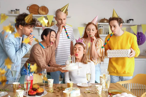 Young woman making wish at birthday party with her friends