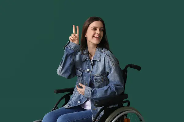 Молодая Женщина Инвалидной Коляске Показывает Победный Жест Зеленом Фоне — стоковое фото