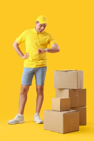 Male Courier Parcels Looking Smartwatch Yellow Background — Stock Photo, Image