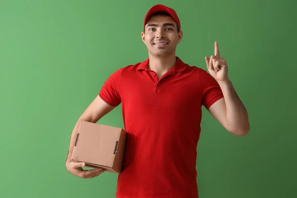 Männlicher Kurier Mit Paket Zeigt Auf Etwas Auf Grünem Hintergrund — Stockfoto