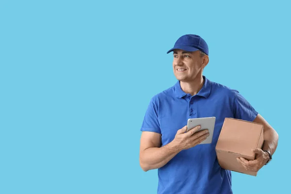 青い背景にタブレットコンピュータと小包が付いている成熟した宅配便 — ストック写真
