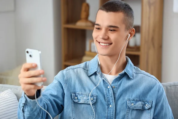 Young man with mobile phone video chatting at home