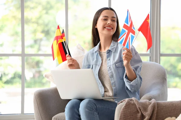 Young woman with different flags learning English language online at home