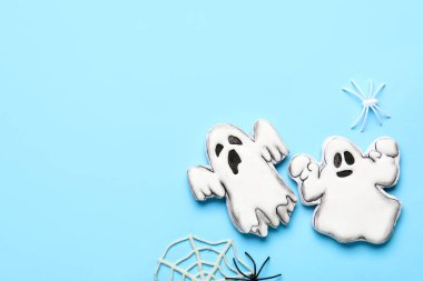 Hayalet şeklinde lezzetli kurabiyeler ve mavi arka planda Cadılar Bayramı kutlaması için internet.