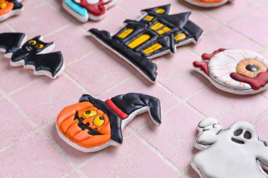 Cadılar Bayramı kutlamaları için farklı lezzetli kurabiyeler pembe fayans arka planda, yakın plan