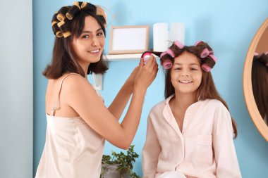 Annesi banyoda kıvırcık saçlı küçük bir kız.