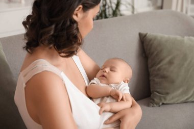 Bebekli genç bir kadın evdeki kanepede oturuyor, yakın plan.