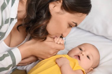 Yatak odasında bebeğini öpen genç bir kadın, yakın plan.