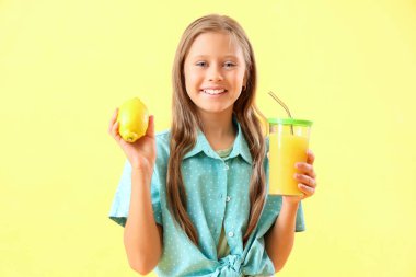 Sarı arka planda limonlu küçük kız ve bir bardak taze meyve suyu.