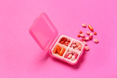 Pembe arka planda farklı haplar içeren konteyner