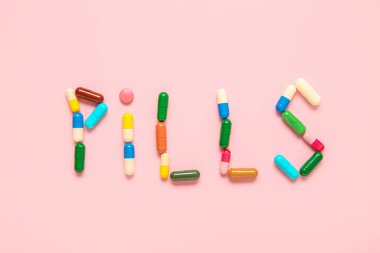 Pembe arka planda farklı ilaçlardan yapılmış Kelime PILLS