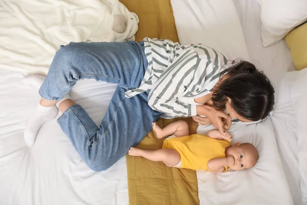 ベッドの上に横たわっている赤ん坊を持つ若い女性 トップビュー — ストック写真