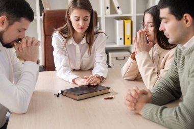 Bir grup iş adamı masada kutsal kitapla dua ediyor.