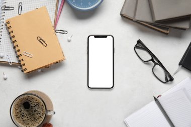 Modern cep telefonu, kırtasiye malzemesi ve açık arkaplanda bir fincan kahve ile kompozisyon