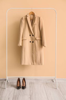 Askıda asılı şık bir ceket ve renkli duvarda yüksek topuklu ayakkabılar.