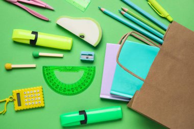 Kağıt torba ile kompozisyon ve yeşil zemin üzerinde farklı kırtasiye