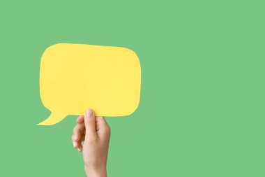 Yeşil arkaplanda konuşma baloncuğu olan bir kadın el