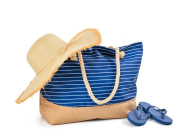 Hasır şapkalı şık bir plaj çantası ve beyaz arka planda parmak arası terlikler.