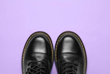 Leylak arkaplanda şık siyah deri çizmeler