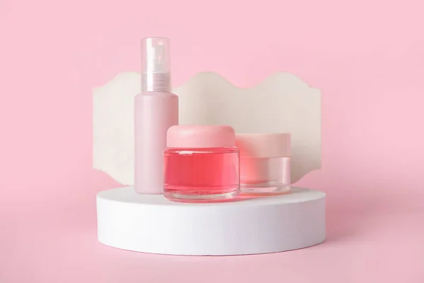 Composition with cosmetic products and podiums on pink background