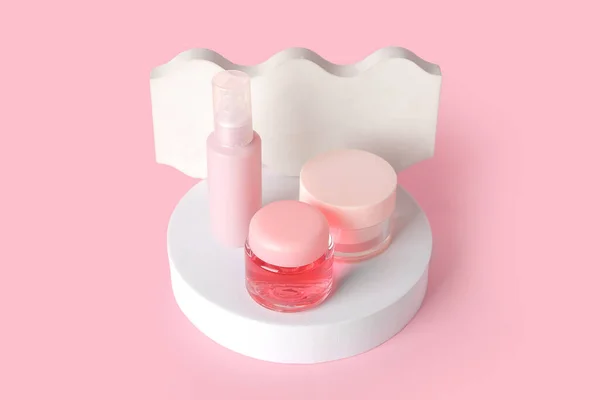 Composition with cosmetic products and podiums on pink background