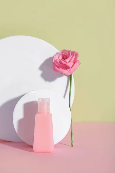 Composition with bottle of cosmetic product, plaster podiums and rose flower on color background