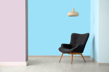 Mavi duvarın yanındaki gri koltuk ve lamba