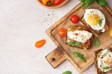 Hafif arka planda yumurta ve lezzetli sandviçlerden oluşan ahşap tahta bir tahta.