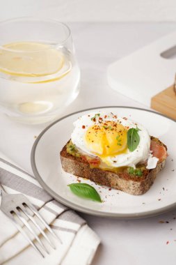 Gri zemin üzerinde yumurta olan lezzetli bir sandviç tabağı.