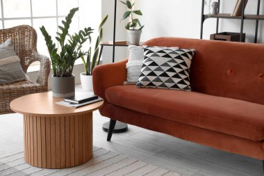 Modern oturma odasının içinde rahat bir kanepe ve sehpanın üzerinde çiçek var.